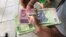 A man in Harare holds bondnotes issued by Reserve Bank of Zimbabwe, Oct. 15, 2018. The introduction of bond notes - a currency Zimbabwe started printing two years ago to ease the situation -- has not helped. (C.Mavhunga/VOA)