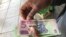 A man in Harare holds bondnotes issued by Reserve Bank of Zimbabwe, Oct. 15, 2018. The introduction of bond notes - a currency Zimbabwe started printing two years ago to ease the situation -- has not helped. (C.Mavhunga/VOA)
