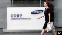  An office worker walks by a logo of Samsung C&T Corp., at its head office in Seoul, South Korea, Friday, July 17, 2015. 