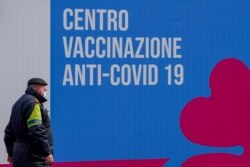 FILE - A security officer walks in front of a COVID-19 vaccination site in Rome, March 16, 2021.