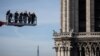 Workers on a crane look at Notre-Dame cathedral site in Paris, France.