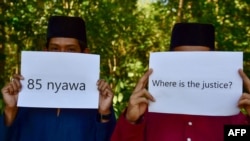 Community members hold up signs in front of a mass grave for victims of the Oct. 25, 2004, Tak Bai Massacre in which 85 Muslims died, most of them by suffocating in Thai army trucks, at a cemetery in Thailand's southern province of Narathiwat on Oct. 25, 2024.