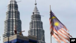 Bendera Malaysia yang sudah tampak robek terpasang di depan Menara Petronas di Kuala Lumpur, Malaysia, pada 10 April 2018. (Foto: AP/Vincent Thian)