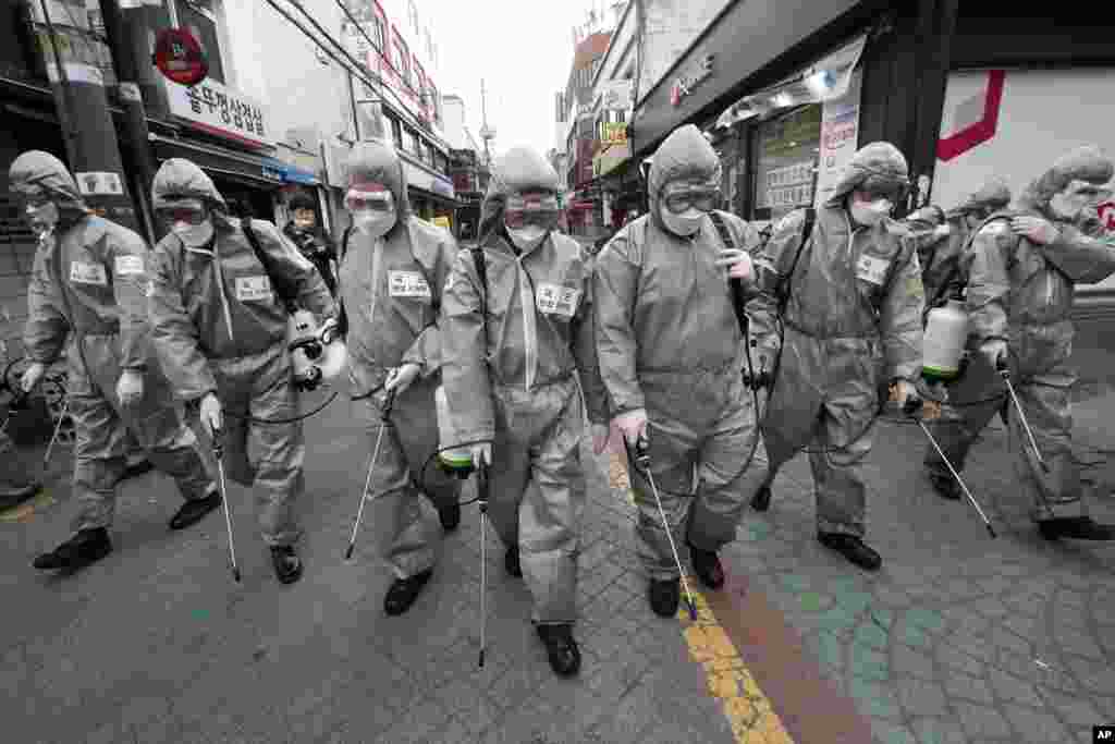 Army soldiers wearing protective suits spray disinfectant as a precaution against the new coronavirus at a shopping street in Seoul, South Korea.