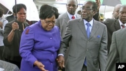 FILE: Zimbabwean President Robert Mugabe (R) is greeted by Vice President Joice Mujuru (L) after a trip to Singapore that had ignited speculation the veteran leader was seriously ill, as he returns home to Harare, Zimbabwe, April 12, 2012.