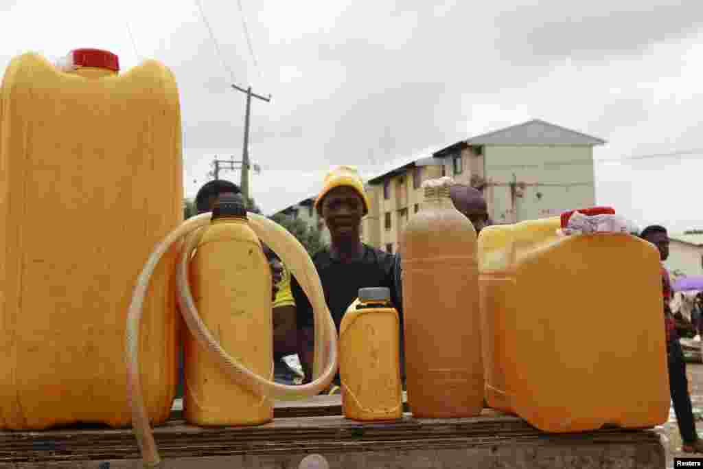 Um homem senta-se atrás dos bidons de combustível. Abuja, Nigéria, 25 de Maio, 2015