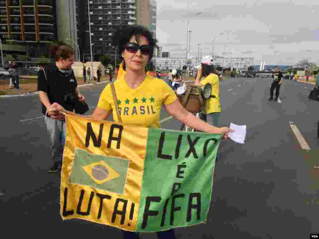 A protester holds a banner that reads in Portuguese "Fight, FIFA is Trash" during a World Cup protest in Brasilia, Brazil, June 23, 2014. (Nicolas Pinault/VOA)