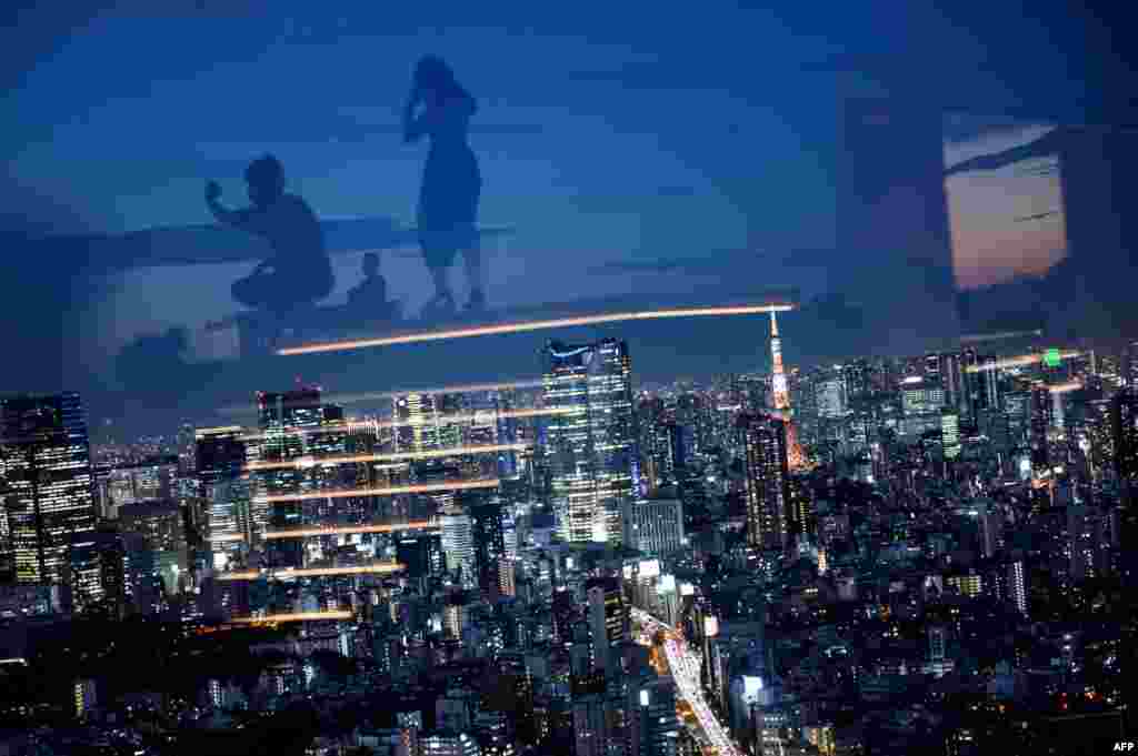 일본 도쿄의 시부야 전망대 유리창에 야경을 관람하는 방문객들의 모습이 비치고 있다. 