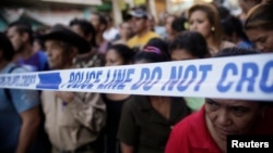 People stand behind a police line at a crime scene in Tegucigalpa, Honduras, Nov. 19, 2013.