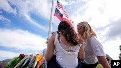 Two students view a memorial as the flags fly half-staff after a shooting Wednesday at Apalachee High School, Sept. 5, 2024, in Winder, Ga. 