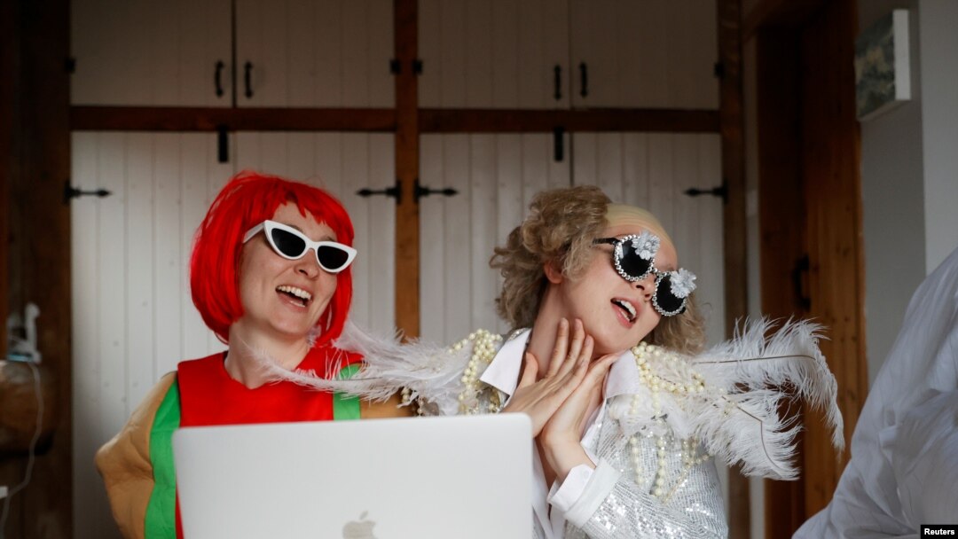 Emily berdandan seperti Elton John dan Molly sebagai Lady Gaga menyaksikan konser "One World: Together at Home" dari rumah mereka di Henton, Inggris, di tengah pandemi virus corona (Covid-19), Sabtu, 18 April 2020. (Foto: Reuters)