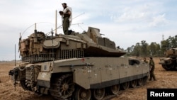 Izraelski vojnik se moli dok stoji na tenku, na izraelskoj strani granice između Izraela i pojasa Gaze