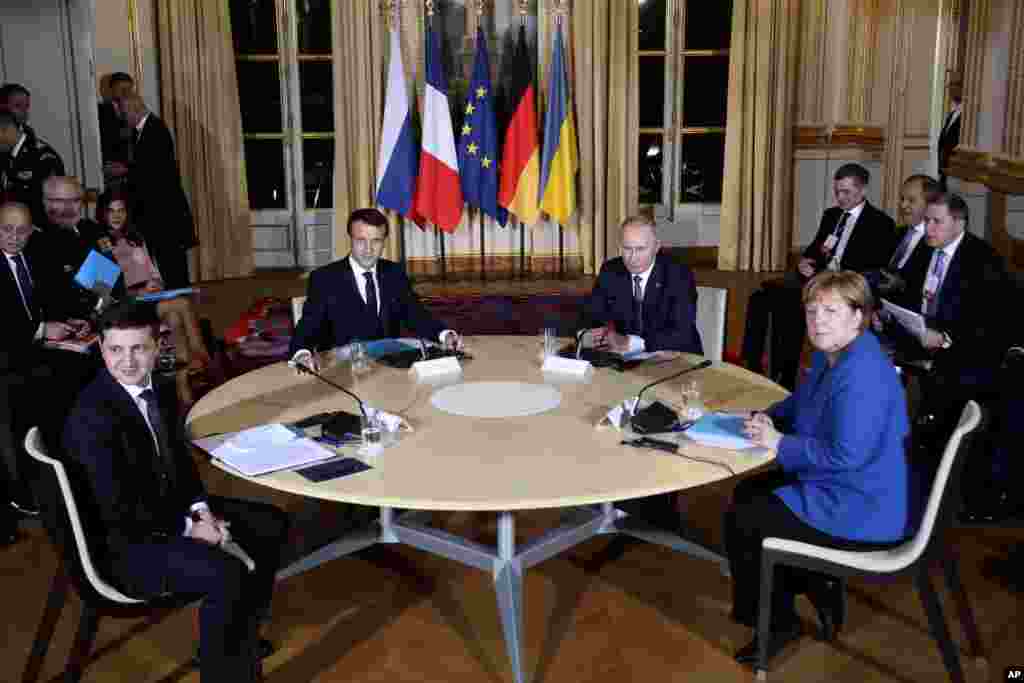 French President Emmanuel Macron, center left, Russian President Vladimir Putin, center right, German Chancellor Angela Merkel and Ukrainian President Volodymyr Zelenskiy, left, attend a working session at the Elysee Palace in Paris, to find a way to end.