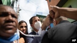 El líder de la oposición venezolana Juan Guaidó choca con el puño de un residente durante una visita al barrio La Lucha de Caracas, Venezuela. Diciembre 10, 2020. Foto: AP.