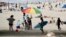 Beachgoers converge under a pier in Huntington Beach, Calif., April 30, 2020.