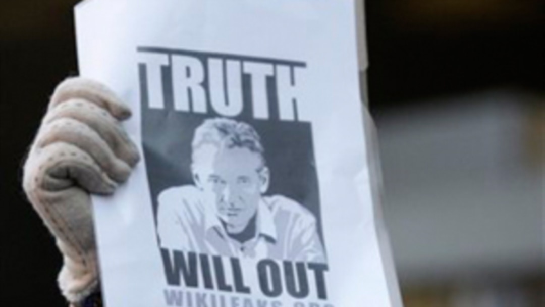Seorang pendukung Julian Assange mengangkat sebuah poster di depan Pengadilan Westminster di London di mana Assange dibawa ke depan hakim pada tanggal 7 Desember 2010.