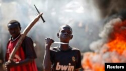 FILE - A boy gestures in front of a barricade on fire during a protest after French troops opened fire at protesters blocking a road in Bambari May 22, 2014. 