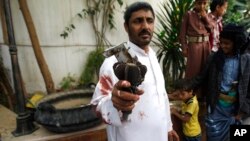 A Houthi Shiite rebel holds part of a projectile launched by Yemeni forces during clashes between Yemeni forces and Houthi militants in Sanaa, Yemen, Sept. 19, 2014. 