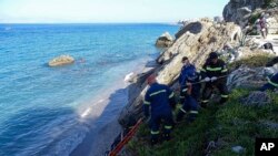 Petugas SAR menarik jenazah seorang migran dari pantai setelah kapal karam di Pulau Rhodes, Yunani tenggara, Senin, 23 November 2020. (Foto: via AP)