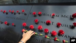 Norma Molina, de San Antonio, Texas, coloca flores en los nombres de bomberos en el Memorial del 11 de septiembre en la ciudad de Nueva York el 9 de septiembre, de 2019.