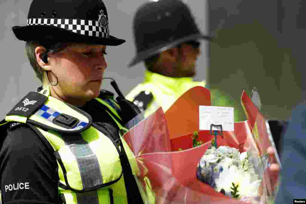 A police officer carries a bunch of flowers with a message of sympathy near Borough Market after an attack left 7 people dead and dozens injured in London, June 4, 2017. 