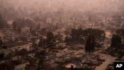 FILE - Smoke lingers over a neighborhood devastated by the Eaton fire, Jan. 9, 2025, in Altadena, Calif.