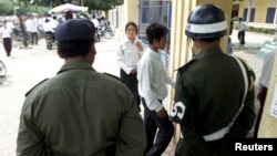 Cambodian military police stand guard as students walk through the gate​ of a school in Phnom Penh, file photo. 