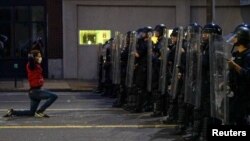 Čovek na kolenima ispred kordona policije u Sent Luisu, u Misuriju (Foto: Reuters/Lawrence Bryant)