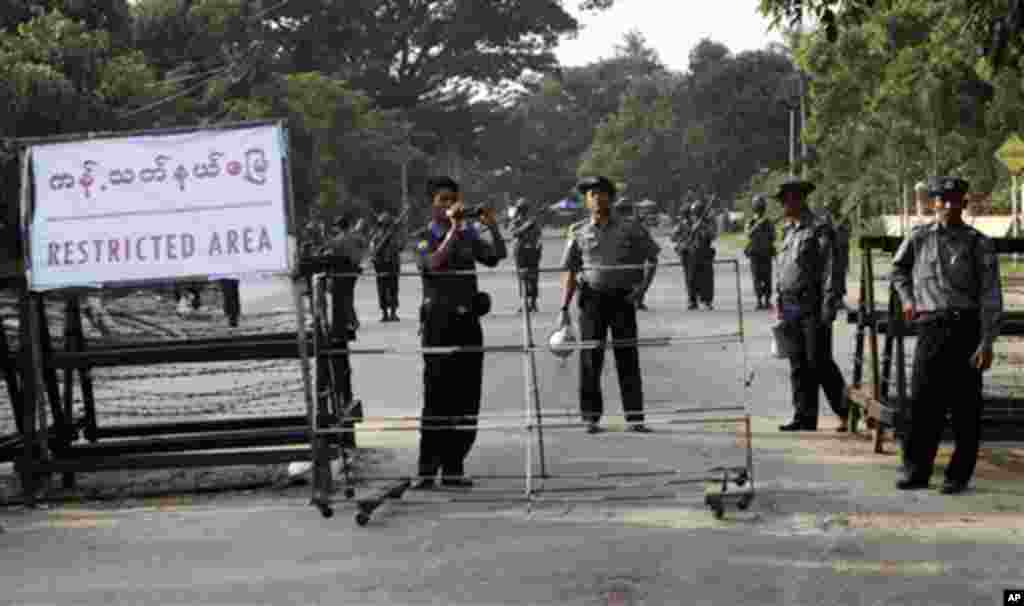 A riot police officer shoots video of supporters of Burma's pro-democracy leader Aung San Suu Kyi on a road leading to the home of Suu Kyi in Rangoon, 13 Nov 2010.