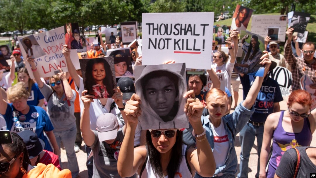 A small crowd stands for a moment of silence during a protest against the National Rifle Association in Dallas, May 5, 2018.