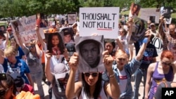 A small crowd stands for a moment of silence during a protest against the National Rifle Association in Dallas, May 5, 2018.