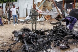FILE - Security forces stand next to wreckage at the scene of a suicide car bomb attack in the capital Mogadishu, Somalia, July 13, 2020.