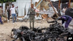Security forces stand next to wreckage at the scene of a suicide car bomb attack in the capital Mogadishu, Somalia, July 13, 2020. 