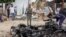 Security forces stand next to wreckage at the scene of a suicide car bomb attack in the capital Mogadishu, Somalia, July 13, 2020. 