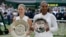Angelique Kerber of Germany holds the winner's trophy after defeating Serena Williams of the United States, right, in the women's singles final match at the Wimbledon Tennis Championships, in London, July 14, 2018.