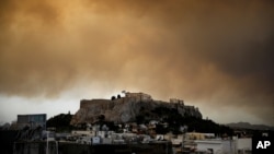 La fumée d'un incendie de forêt à l'extérieur d'Athènes sur le temple du Parthénon au sommet de la colline de l'Acropole, à Athènes, en Grèce, le 23 juillet 2018.