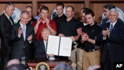 President Donald Trump, accompanied by coal miners and (from left) Interior Secretary Ryan Zinke, Environmental Protection Agency Administrator Scott Pruitt, Energy Secretary Rick Perry, and Vice President Mike Pence, holds up the signed Energy Independence Executive Order, March 28, 2017, at EPA headquarters in Washington.