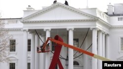 A large red ribbon is installed on the North Portico of the White House to mark World AIDS Day on December 1, in Washington, D.C., November 30, 2012.