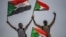 Sudanese protesters flash the victory sign and wave national flags during a rally outside the army headquarters in the capital, Khartoum, April 19, 2019.