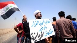 A protester holds a sign that reads "We ask the decision makers to provide the things we are deprived of" during a protest in south of Basra, Iraq July 16, 2018.