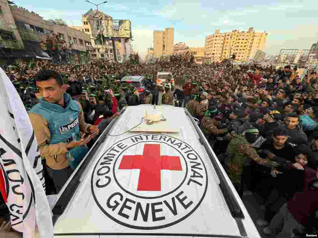 Palestinian Hamas militants and people gather around a Red Cross vehicle before the release of hostages kidnapped during the October 7, 2023, attack on Israel by Hamas, in Gaza City, Jan. 19, 2025. 