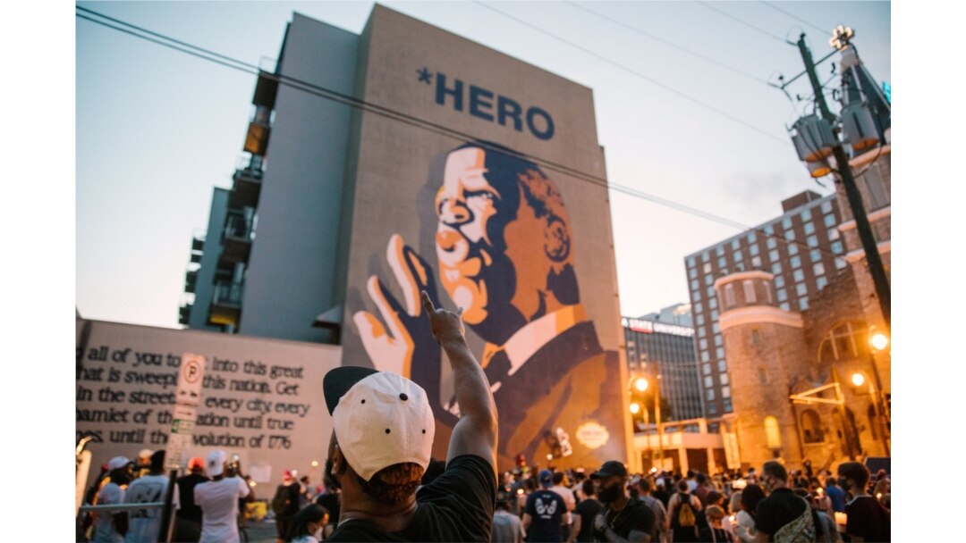 Personas realizan una vigilia frente a un edificio donde se encuentra una imagen del congresista John Lewis, en Atlanta, Georgia.