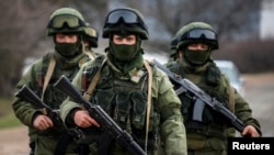 Armed men, believed to be Russian servicemen, march outside an Ukrainian military base in the village of Perevalnoye near the Crimean city of Simferopol March 9, 2014. Shots were fired in Crimea to warn off an unarmed international team of monitors and at