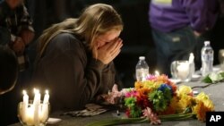 Seorang gadis remaja menutup wajahnya saat berlutut di tempat doa bersama di gereja bagi korban penembakan di SMA Marysville Pilchuck (24/10). (AP/Ted S. Warren)