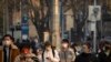 Personas con mascarillas caminan por una calle durante la hora pico matutina en el distrito empresarial en Beijing, el 16 de febrero de 2023.