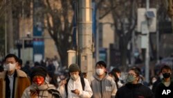 Personas con mascarillas caminan por una calle durante la hora pico matutina en el distrito empresarial en Beijing, el 16 de febrero de 2023.