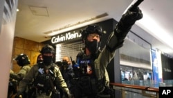 Riot police gesture as they gather at a shopping mall during a demonstration in Hong Kong, Dec. 26, 2019.
