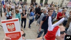 Des manifestants portant des gants aux couleurs du drapeau polonais et exhibant la constitution polonaise organisent une manifestation devant le palais présidentiel, à Varsovie, en Pologne, le 3 juillet 2018.