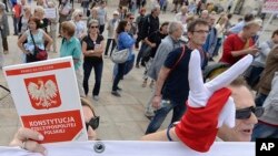 Demonstrators wearing gloves in the colors of the Polish flag and holding a booklet of the Polish constitution stage a protest outside the Presidential Palace, in Warsaw, Poland, July 3, 2018.