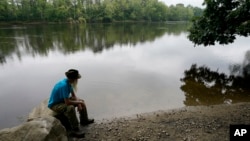 David Lidstone, 81, sits near the Merrimack River, Tuesday, Aug. 10, 2021, in Boscawen, N.H. Lidstone, an off-the-grid New Hampshire hermit known to locals as "River Dave," had been living in a cabin in the woods along the Merrimack River, in Canterbury, 